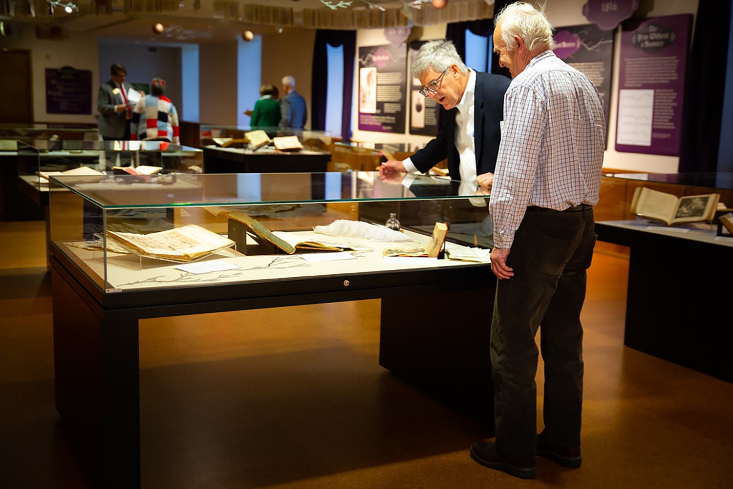 Interior - Two men looking at book under glass