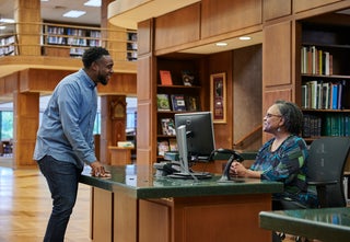 Male patron and reference librarian at front desk