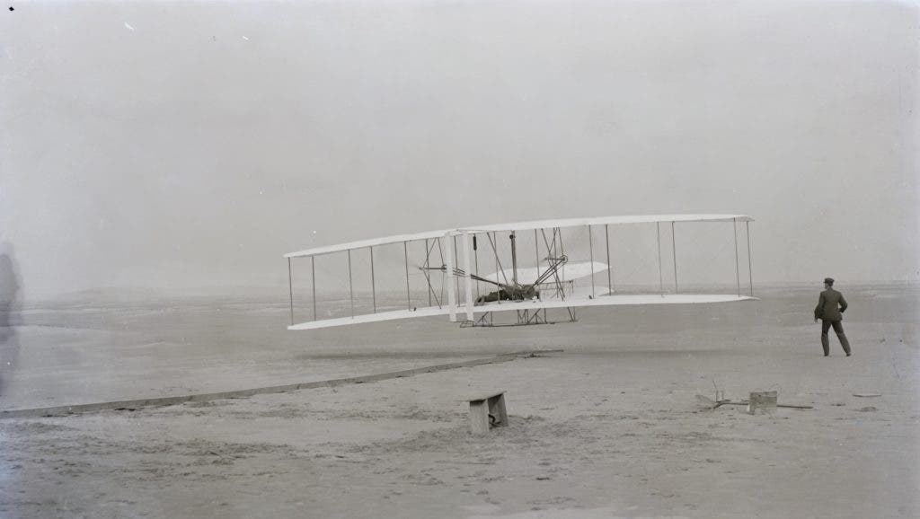 The Wright Flyer takes to the air, December 17, 1903, with Orville piloting the aircraft and his brother Wilbur running alongside. The Wright flyer weighed 750 pounds with a pilot aboard and was powered by a 12-horse- power gasoline engine that turned two 8-foot propellers with a chain-and-sprocket system. The Flyer had a wingspan of 40 feet and was 21 feet in length. Image courtesy of the Library of Congress.