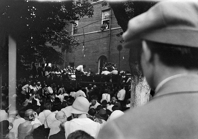 A view from the crowd of William Jennings Bryan (back of bald head, seated, right of center), being cross-examined by Clarence Darrow, standing, July 20, 1925 (photo by William Silverman, now in the Smithsonian Institution archives, here via Wikimedia commons)