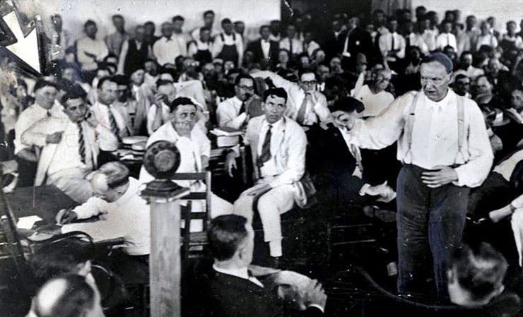 Clarence Darrow speaking at the Scopes Trial, with H.L. Mencken at far left, indicated by an arrow.
