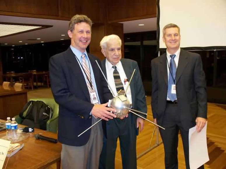 Roger Easton, Sr., center, with Eric Ward, Vice President of Programs, Linda Hall Library, at left, holding a full-scale replica of the satellite aboard Vanguard TV-3, photograph, 2007 (Linda Hall Library)