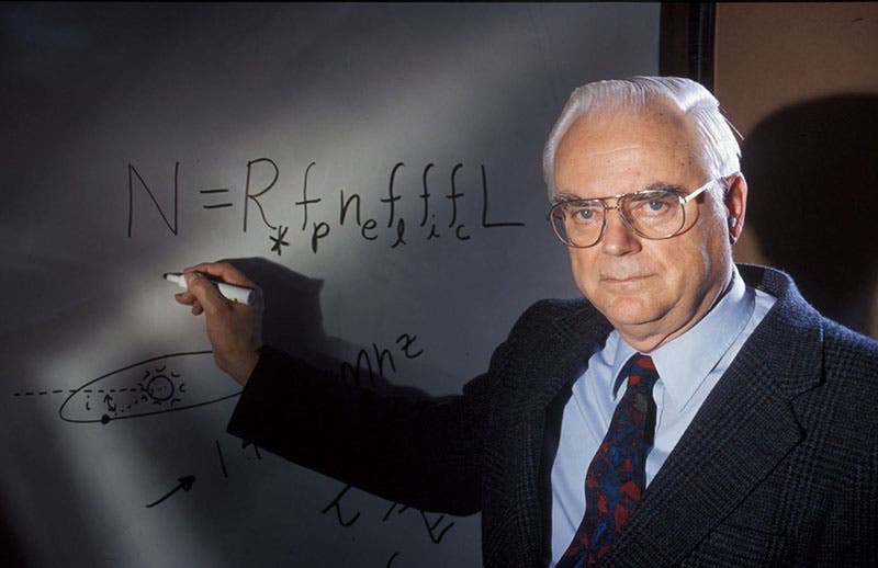 An older Frank Drake, recreating the original blackboard version of his equation, this time with a whiteboard, at the Green Bank conference of 1961, photograph, ca 1985 (seti.org)