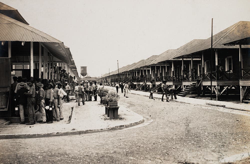 Workers queue up at the outdoor kitchen at Camp Bierd barracks, Cristóbal.
The I.C.C. provided barracks housing to “silver roll” workers without families. The barracks offered racks of cots with little space, and no privacy or personal storage, and sometimes were not screened. Workers were fed at outdoor kitchens that served poor quality food.  