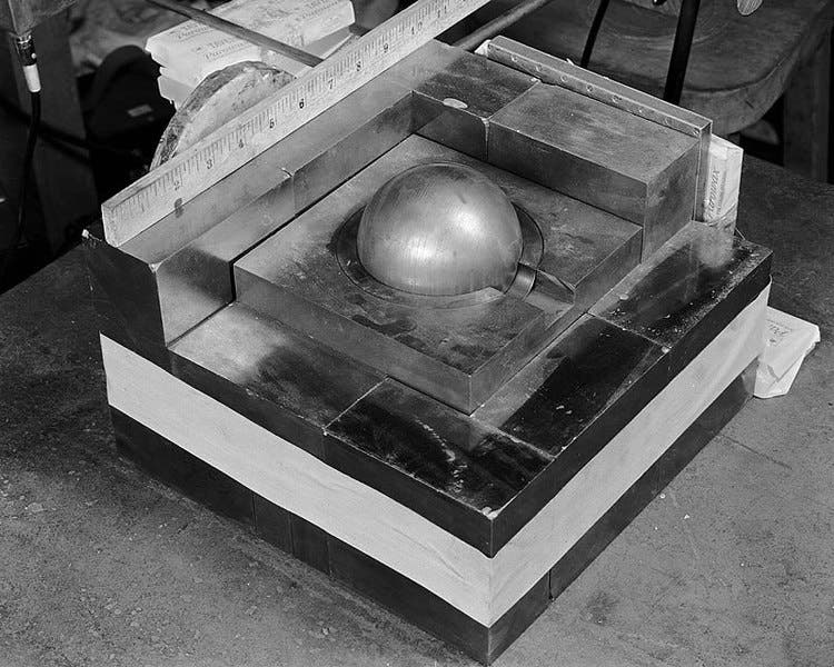 A “Christy pit,” the plutonium sphere nesting at the center of blocks of tungsten carbide on a lab table at Los Alamos, 1945 (Wikimedia commons)