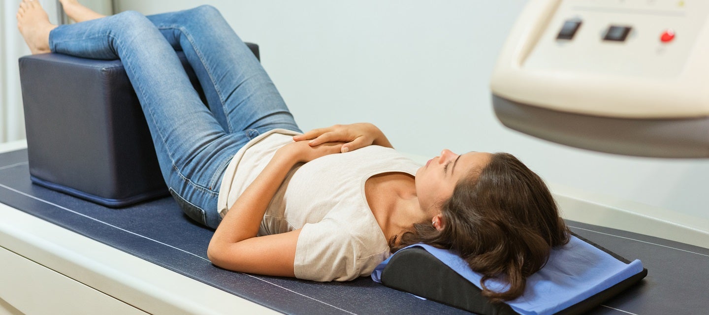 Woman lying on bone densitometry scanner