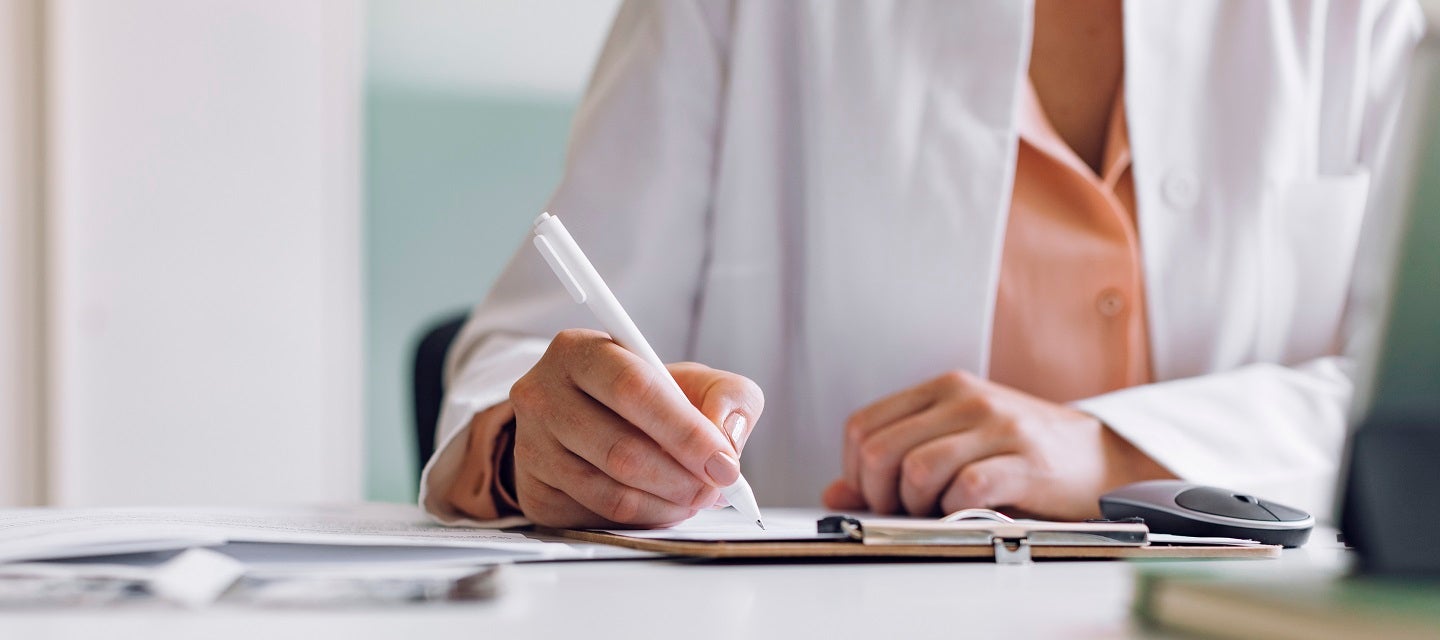 A doctor writing a referral with pen in hand