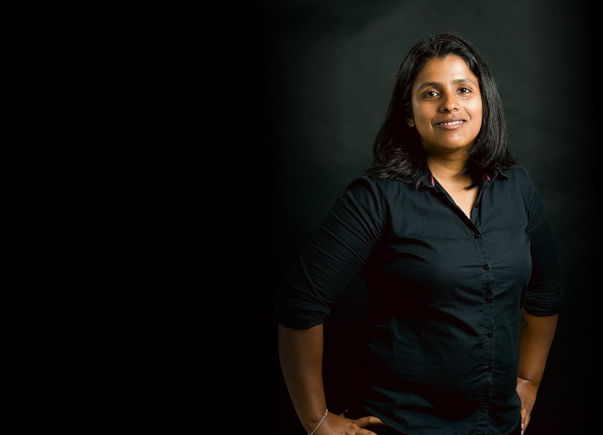 Picture of Luminary employee, Pooja, standing in a black shirt with a black background