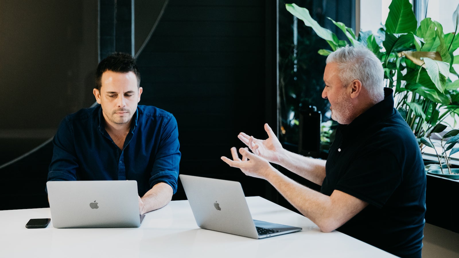 Two men talking with laptops in a digital agency