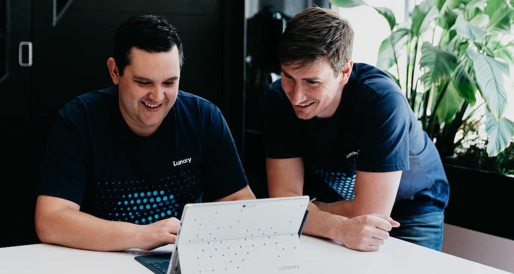 Two men working together over a laptop