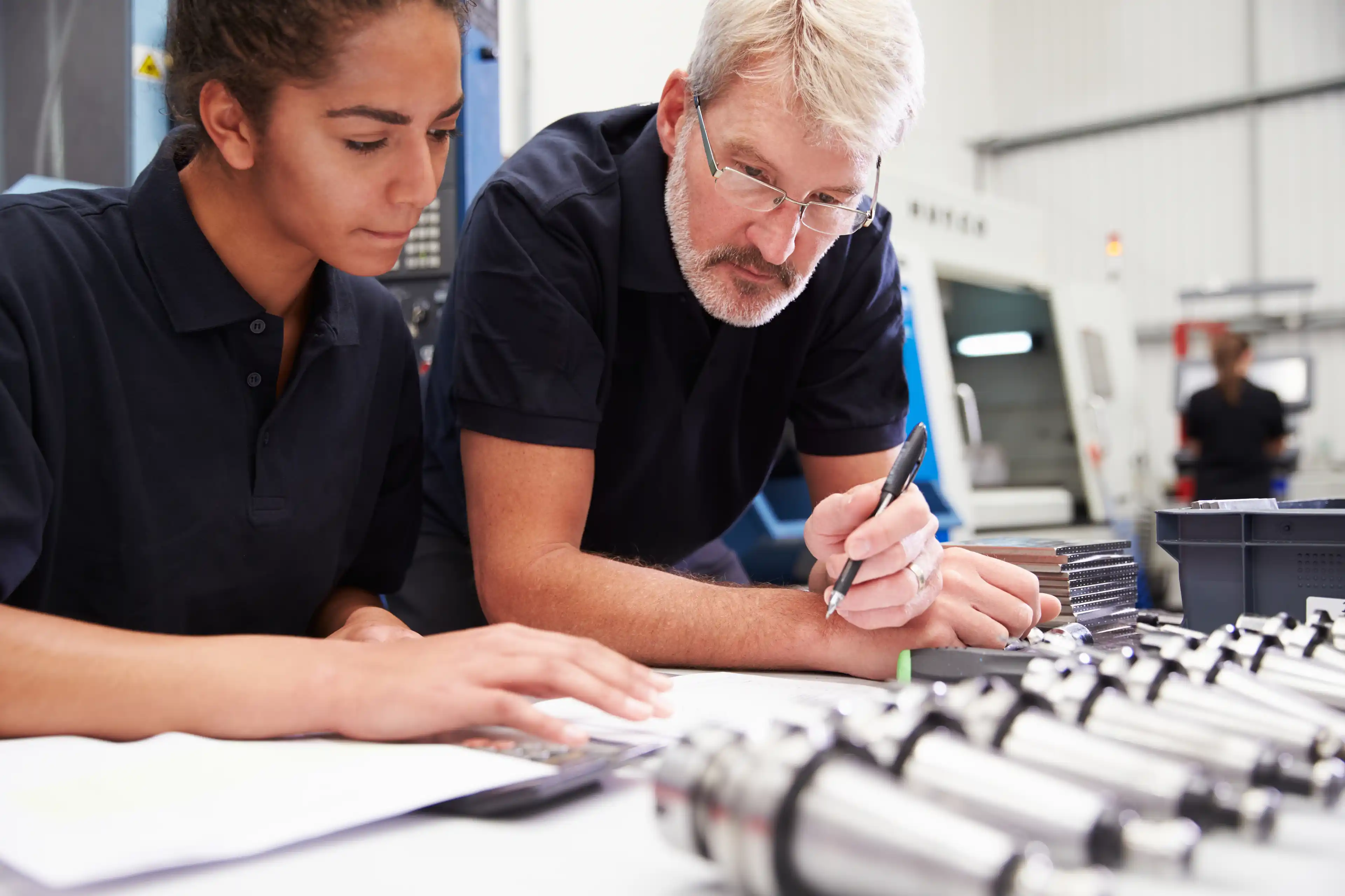 Teacher and engineering student working on paper plans