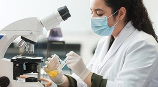 Technician looking at lab samples with a microscope