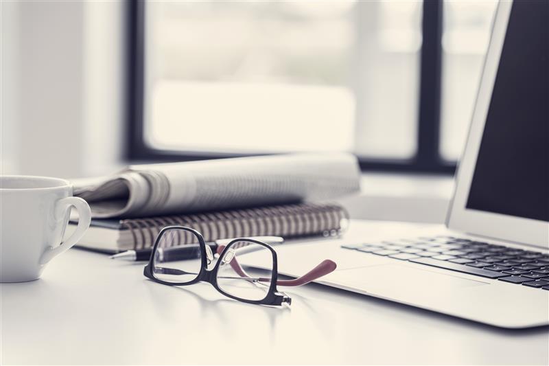 A printed newspaper beside a laptop on a table, symbolizing everyday value moving from print to digital ROI