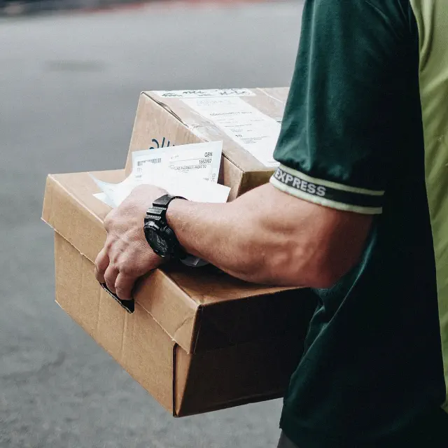 A delivery man carrying packages in the busy streets of New York.