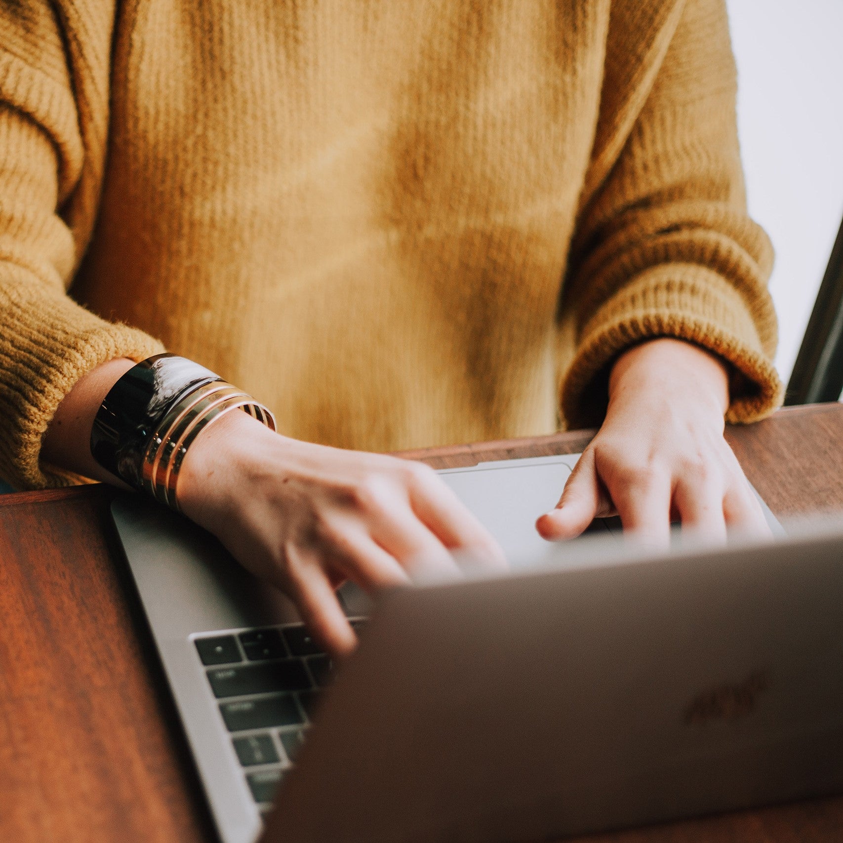 Person with yellow sweater on laptop.