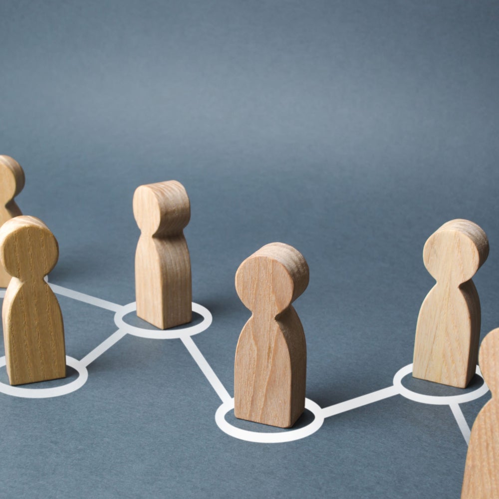Image showing wooden people figurines within white circles connected by white lines.