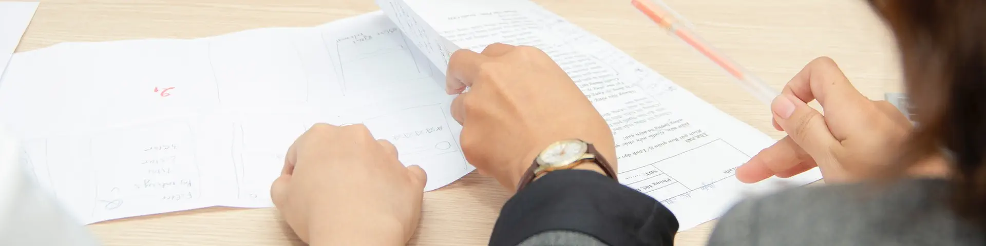 Two individuals filling out paperwork under the guidance of an administrator.