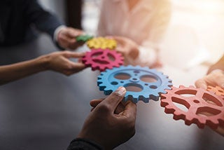 People holding gears together to integrate the teeth