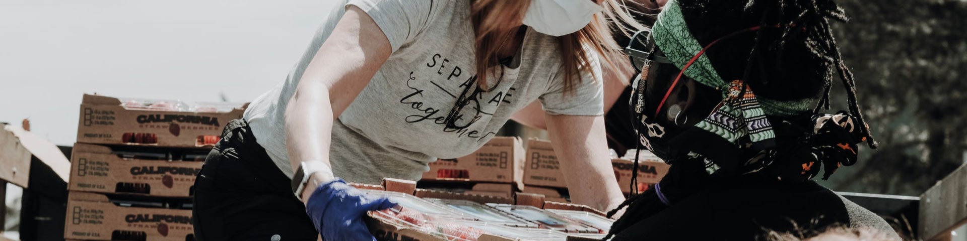 Two volunteers work to unload a shipment of food.