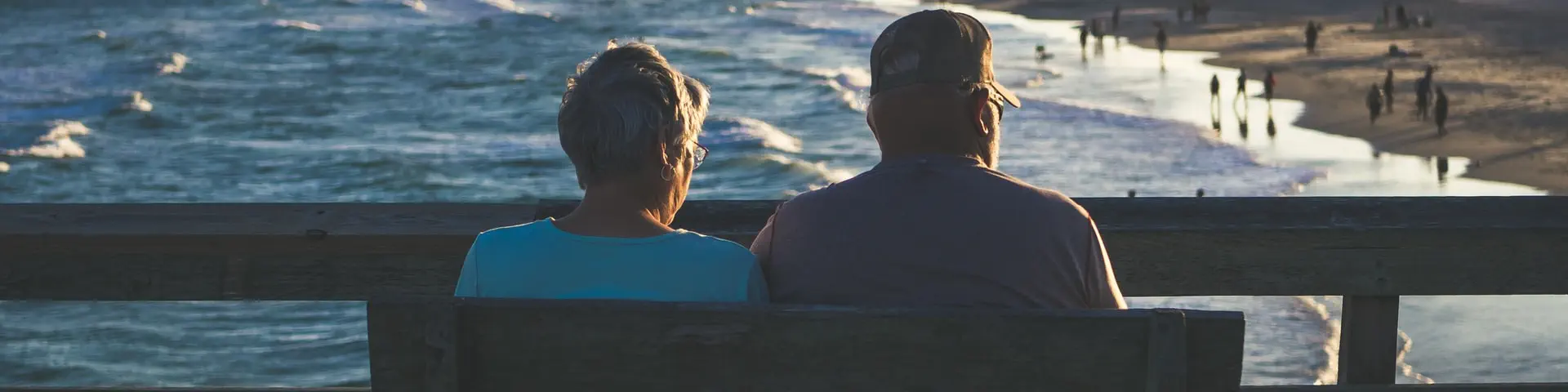 An older couple enjoying their retirement watching the sunset on the beach.