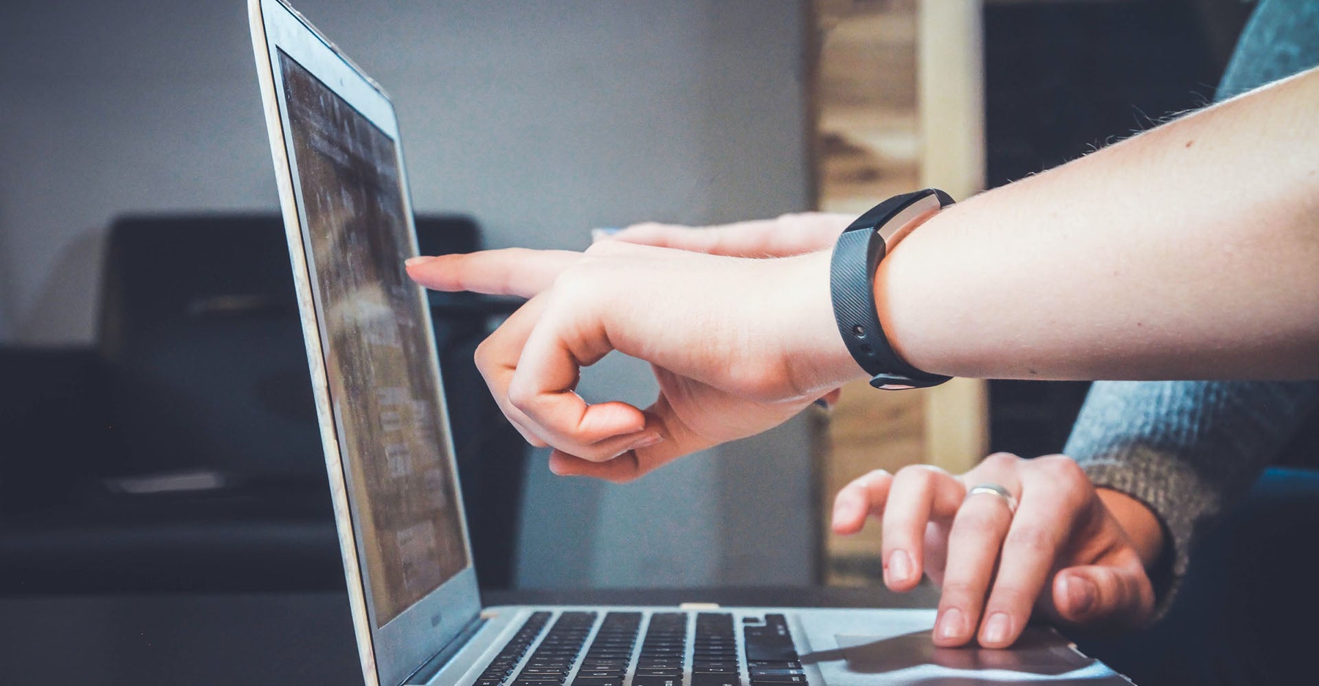 Image of people pointing to laptop