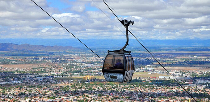 Cabina del teleférico sobrevolando Salta desde el Cerro San Bernardo, con vistas amplias de la ciudad y montañas del valle.