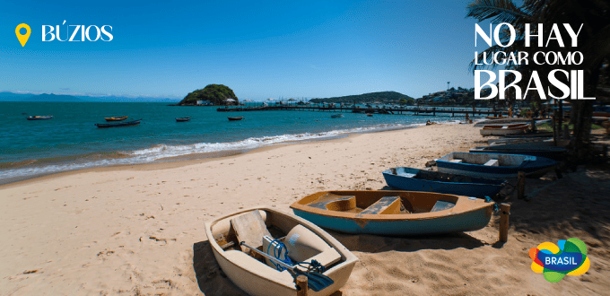 Vista panorámica de la playa de Búzios, Brasil, con botes en la orilla y el mar turquesa al fondo.