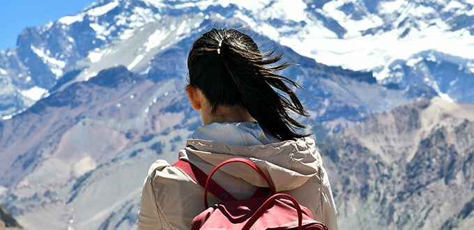Persona con mochila contemplando la Cordillera de los Andes en Mendoza, destacando trekking y aventura en la montaña.