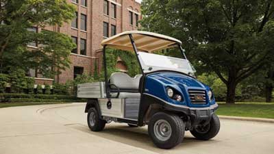 A blue commercial LSV Club Car is parked outside a college campus.
