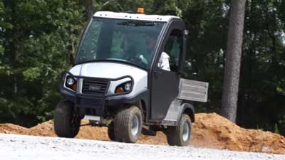 A Club Car Carryall utility vehicle drives outside.