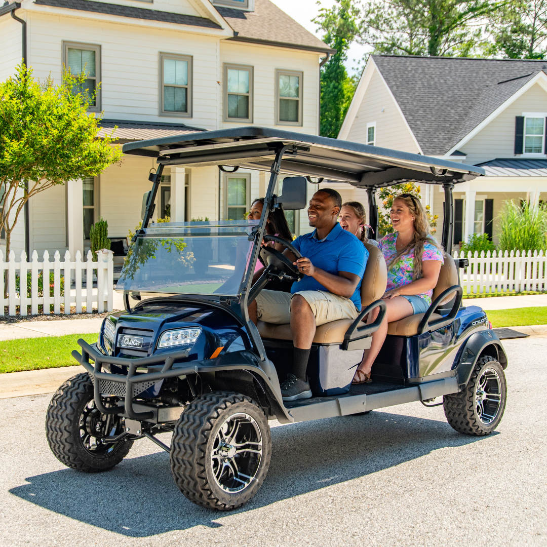 Four people ride in a Club Car Onward on a neighborhood street.