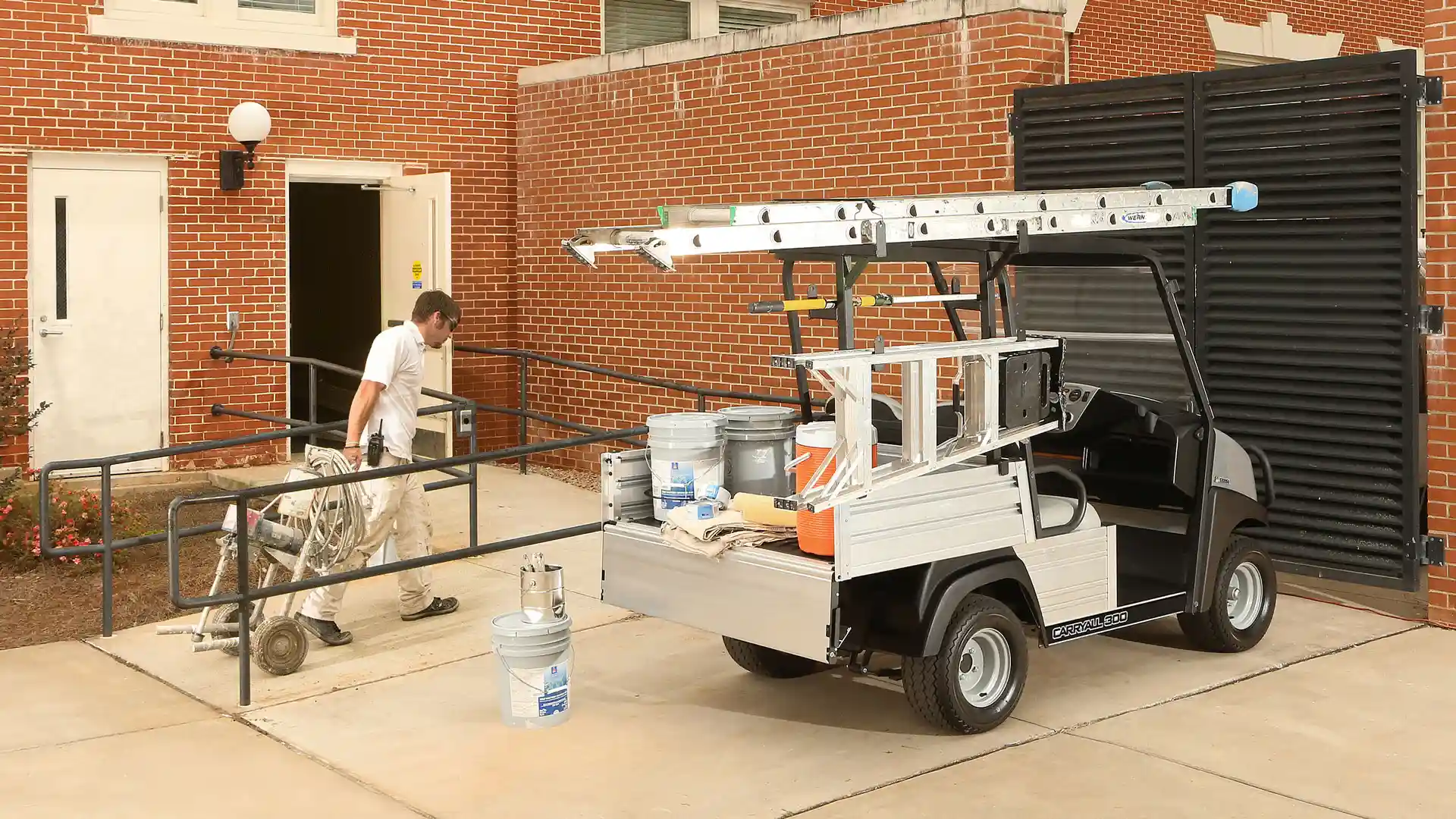 A man carries maintenance equipment toward a Carryall 300.