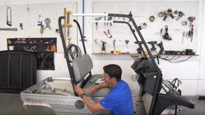 A man installs a part on a Club Car utility vehicle.