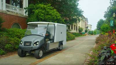 A custom Club Car utility vehicle drives down a sidewalk.