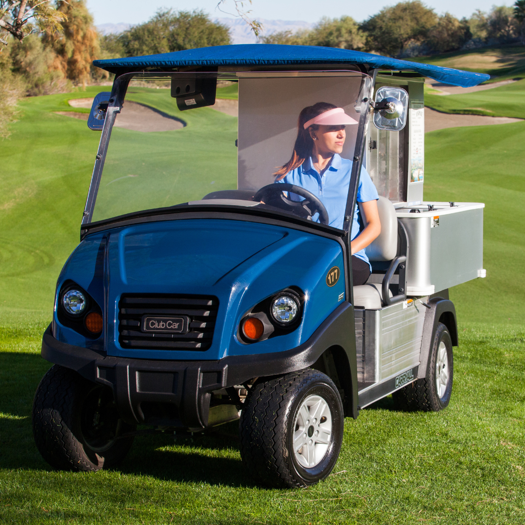 A woman drives Club Car's Cafe Express utility vehicle on a golf course.