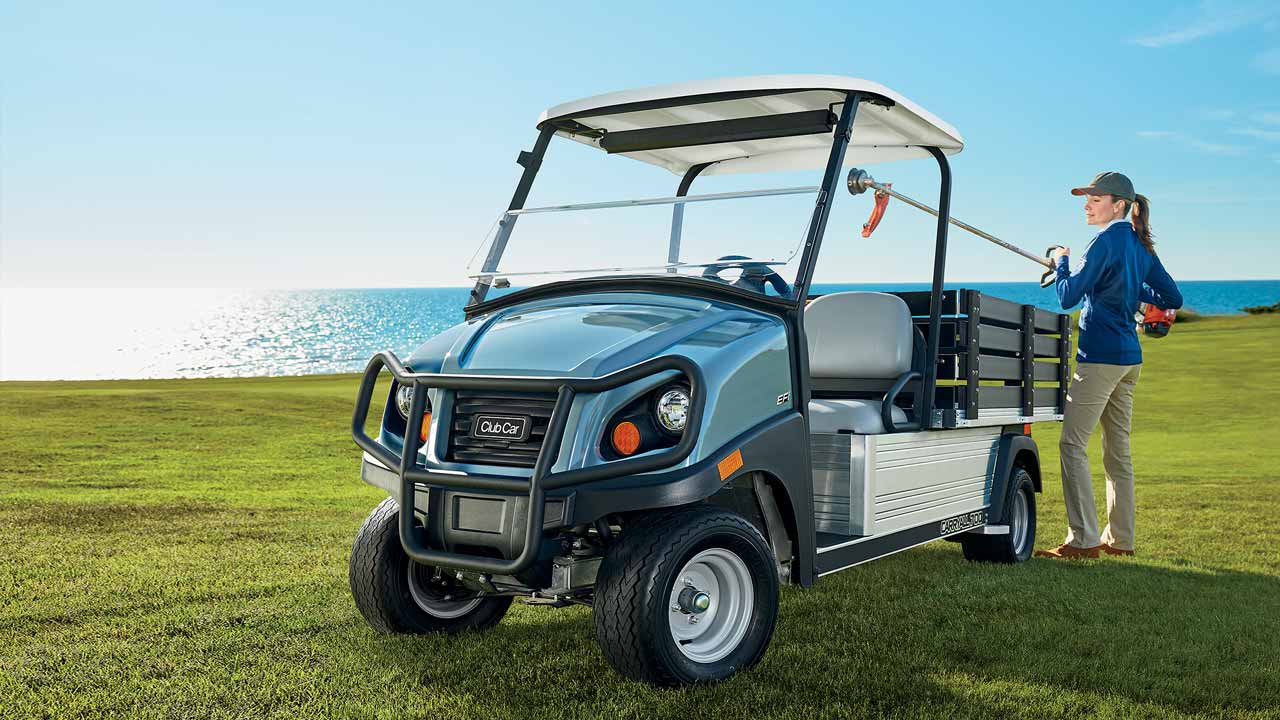 A woman puts equipment back into the Club Car Carryall 700 golf turf utility vehicle on a golf course.