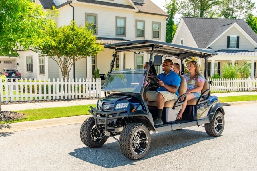 Four people ride a Club Car Onward on a street