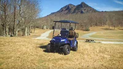 A Club Car Onward drives along grass outside.