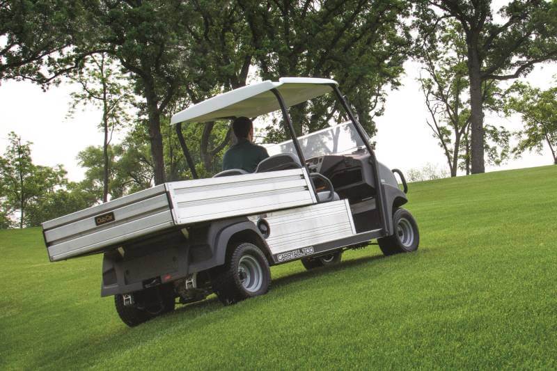 A Club Car Carryall 700 turf utility vehicle drives on a golf course.