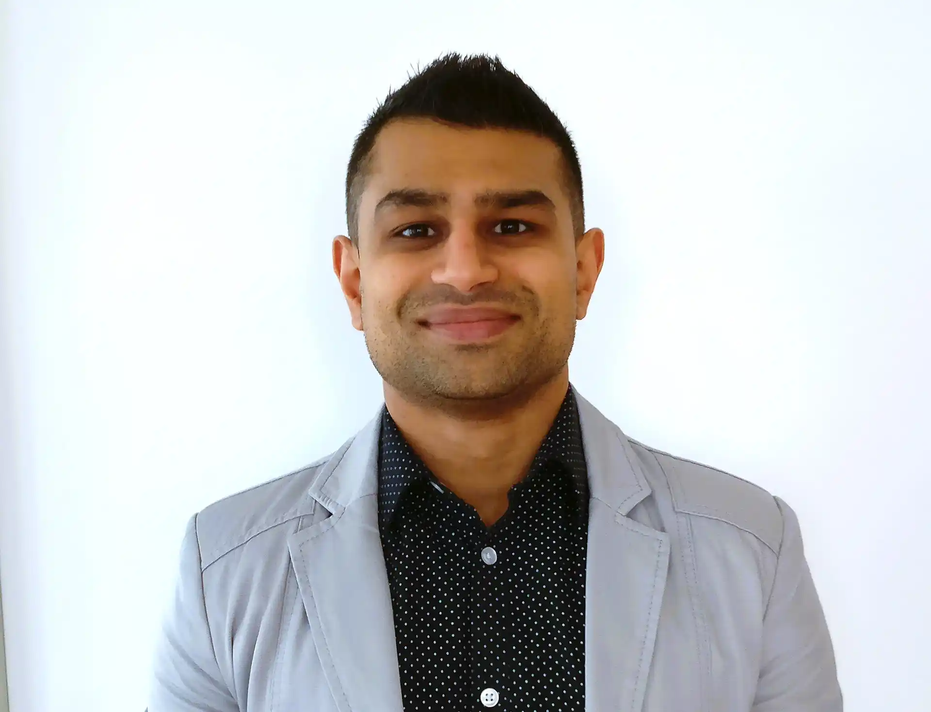 A headshot of a man wearing grey and black