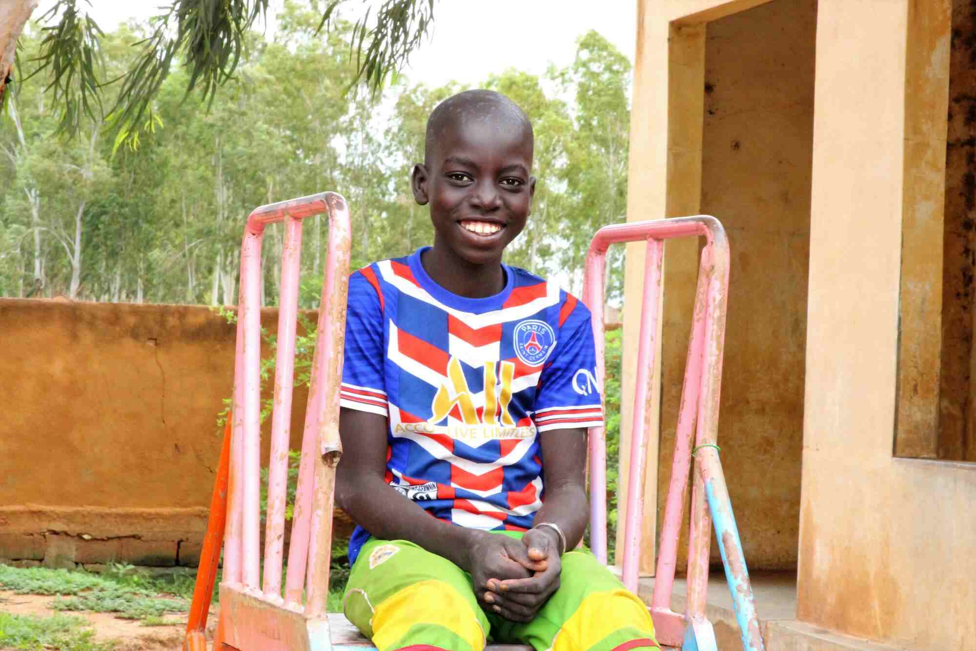 In Mail a young boy sits at the top of a slide and smiles. 