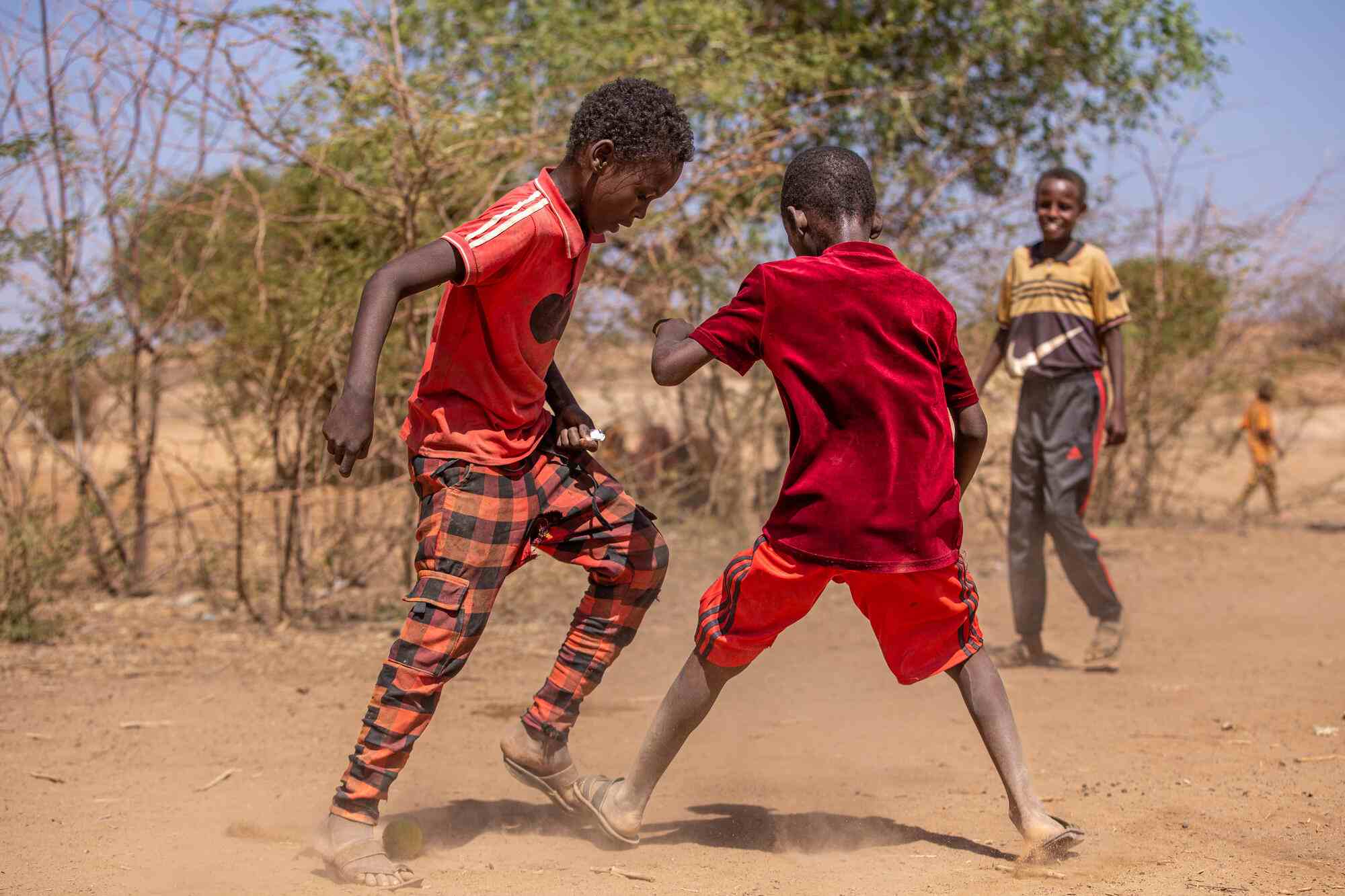 In Somalia, two boys play soccer together with a small ball. 