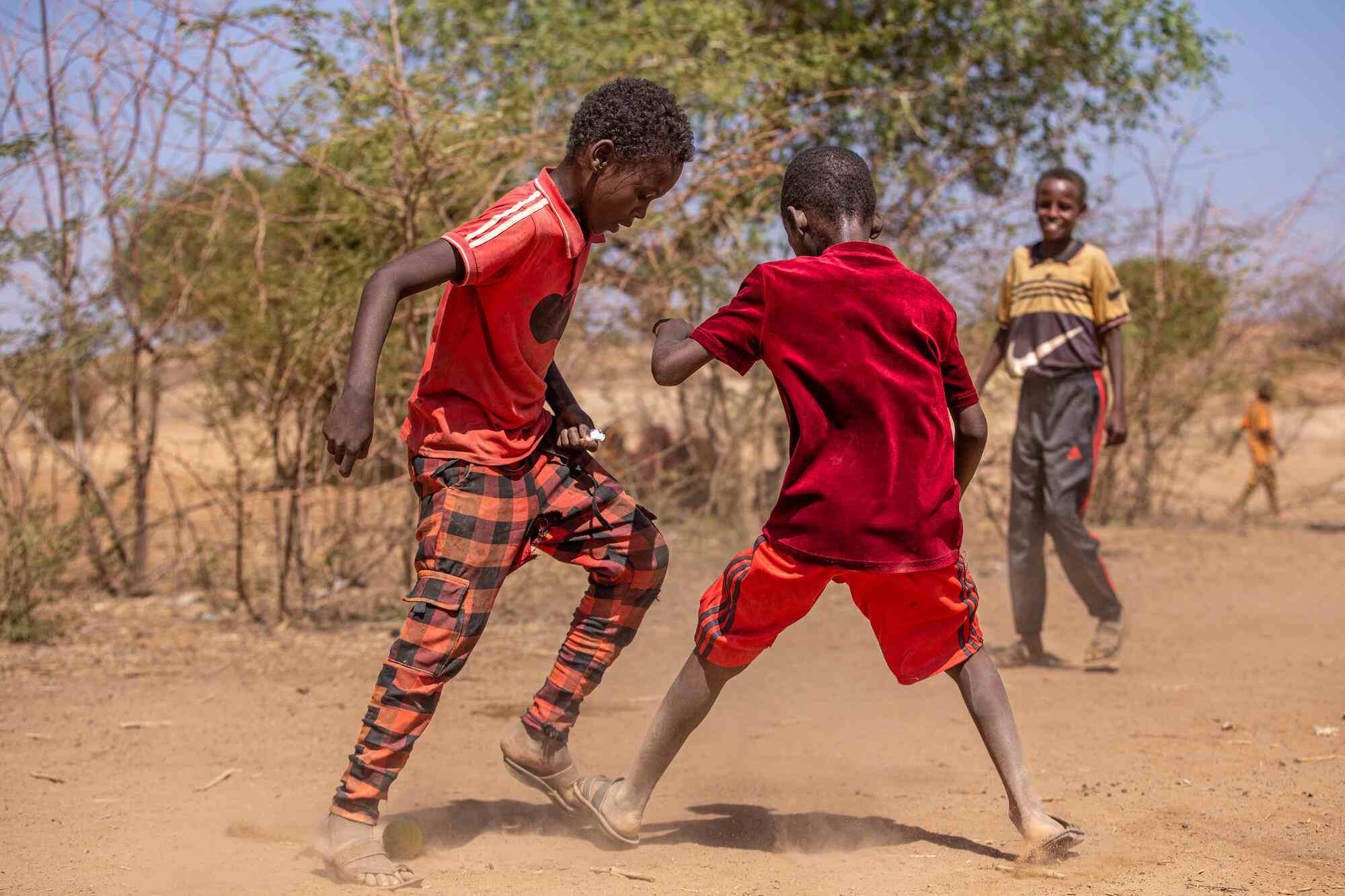 In Somalia, two boys play soccer together with a small ball.