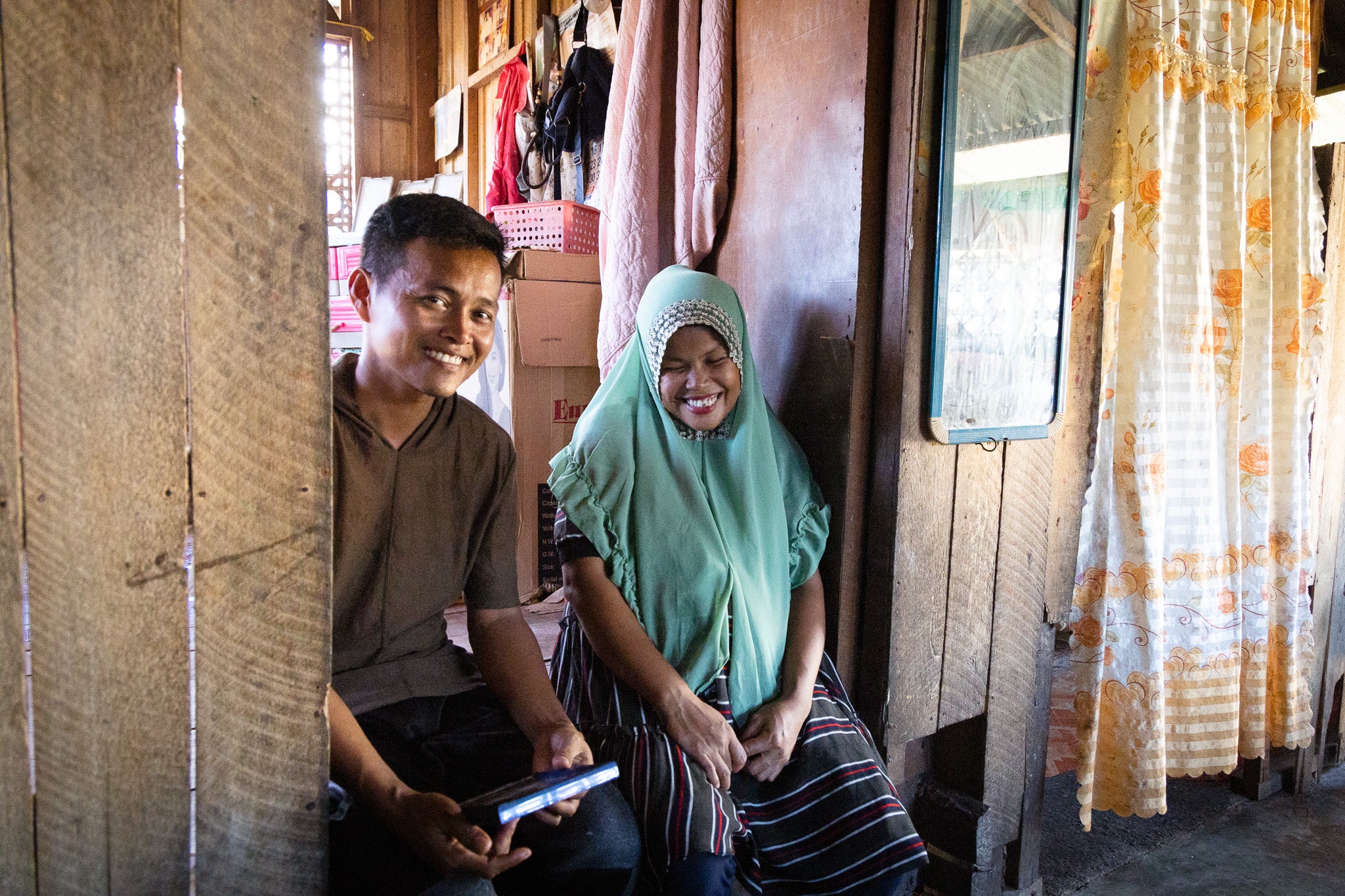 A man and woman sit in a doorway together smiling.