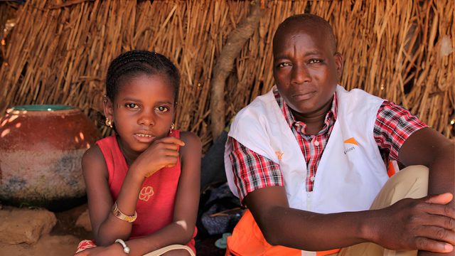 In Central Mali and young girl sit with the Raw Hope Mali project manager inside a makeshift shelter.