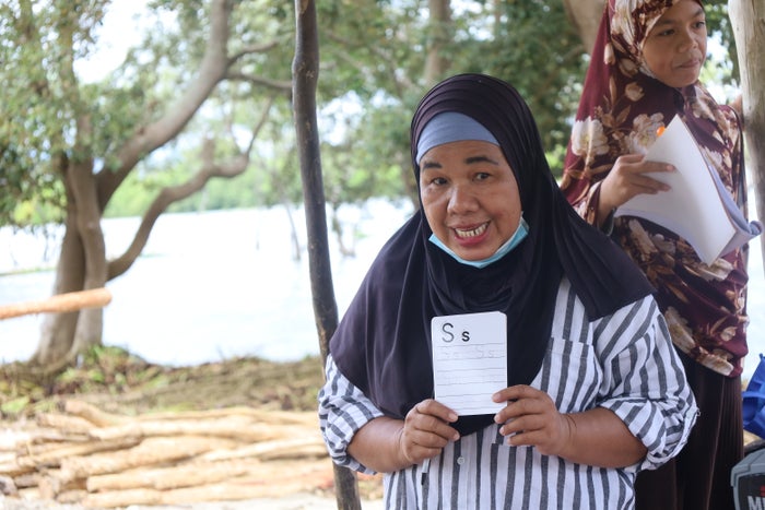 A woman wearing a hijab is showing an educational flash card. 