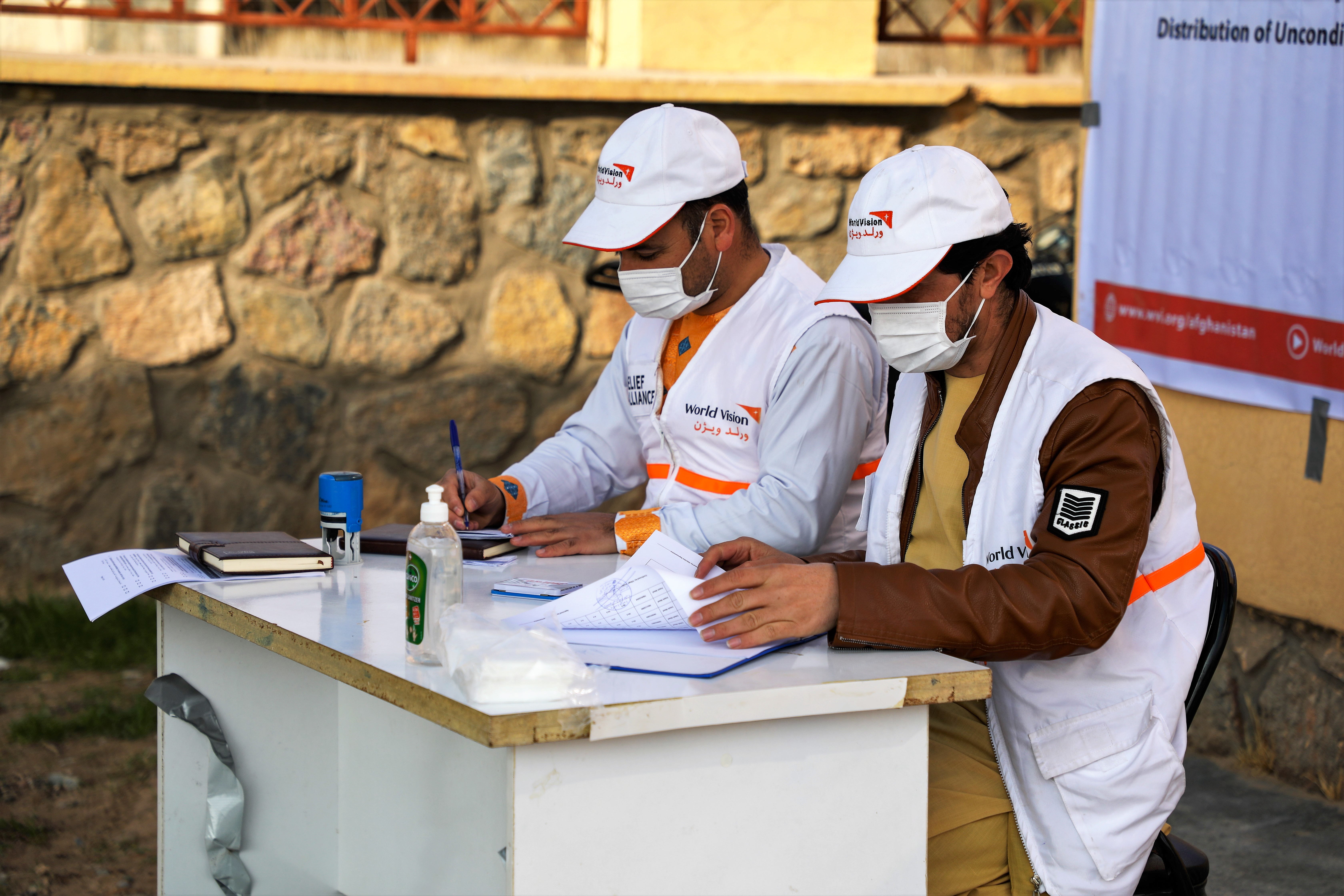 World Vision staff sit at a registration table ready to give out cash vouchers. 