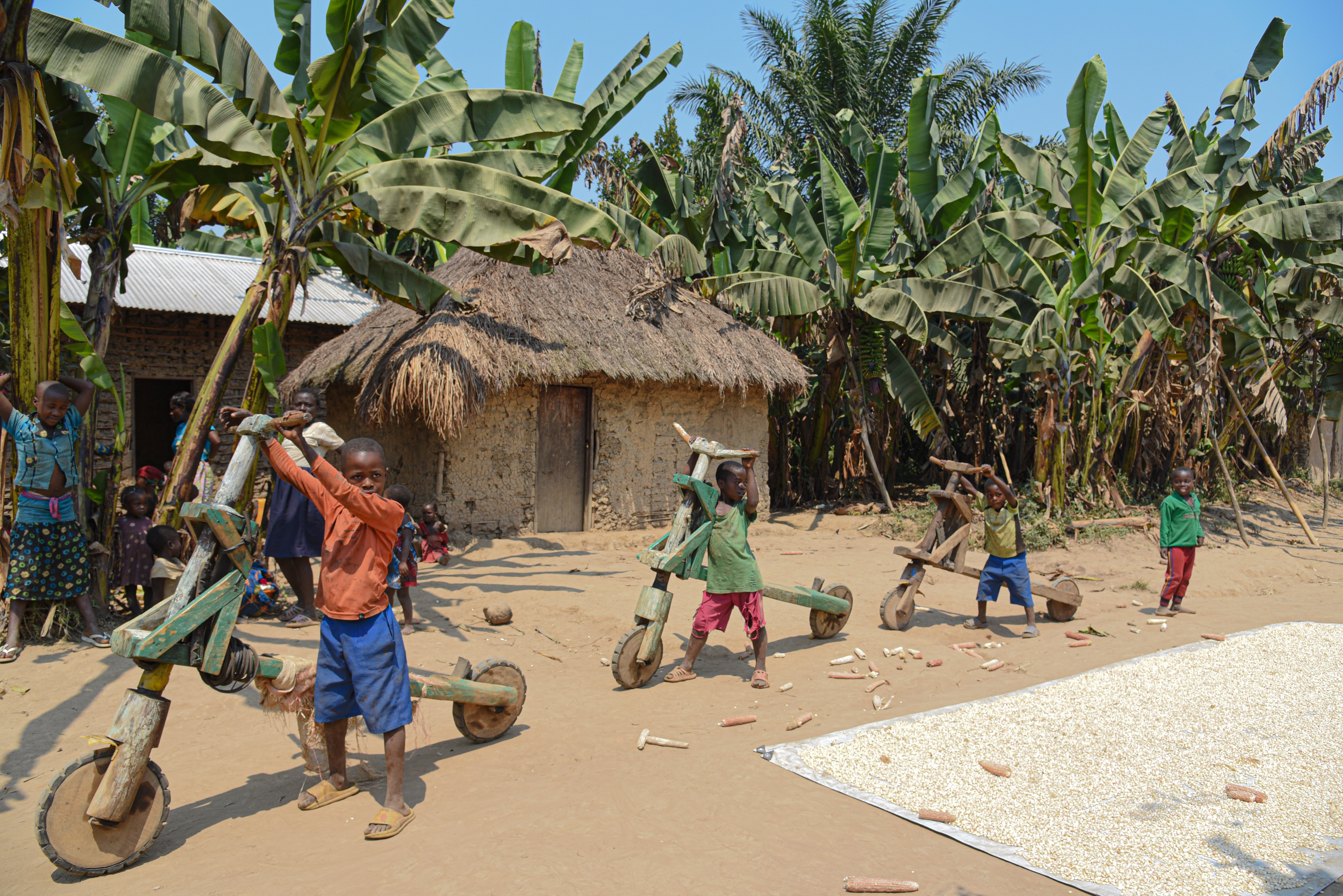 In Binza, DRC, four children stand in a line holding bikes they made from wood.   