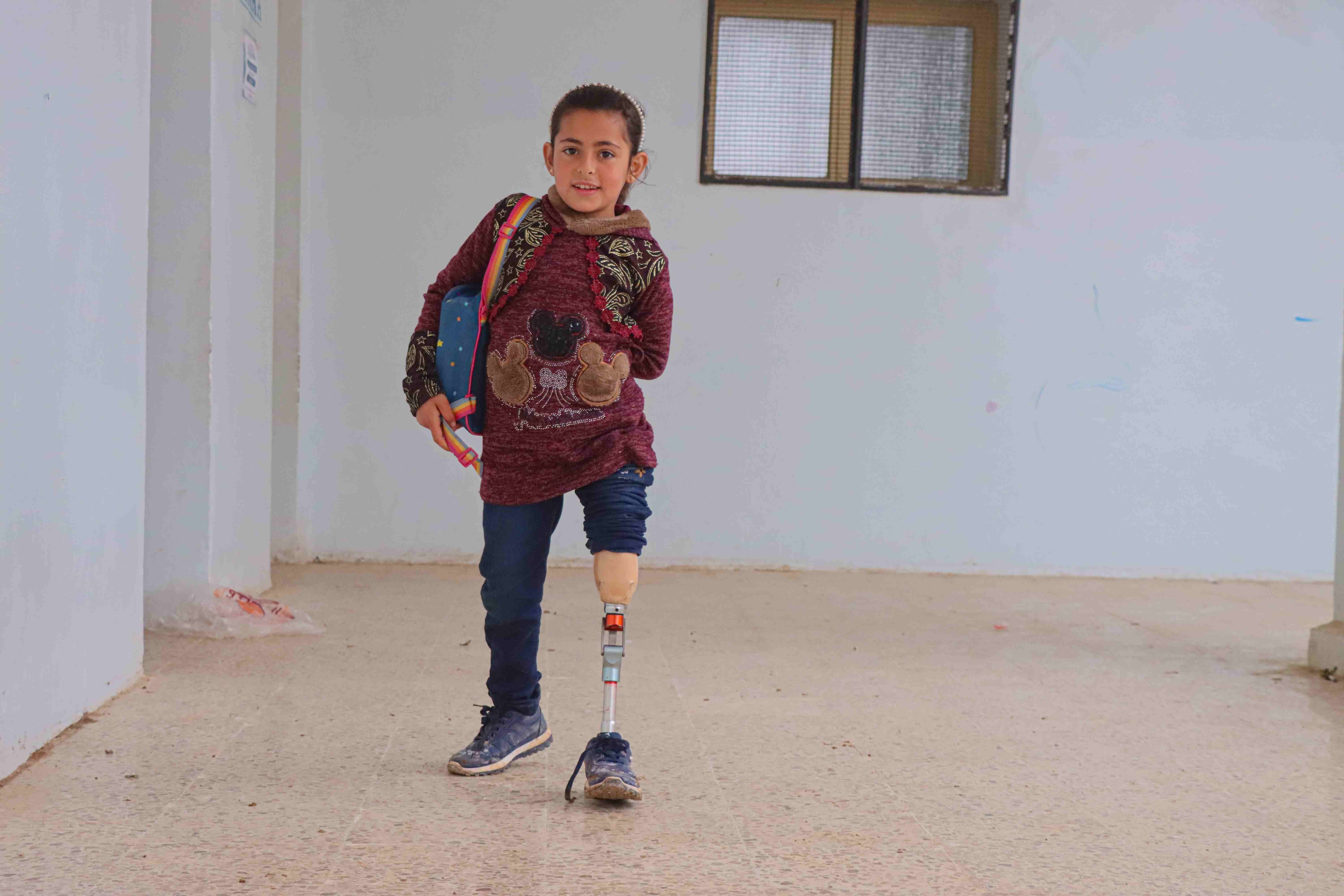 In Syria, a young girl walks using her prosthetic leg.