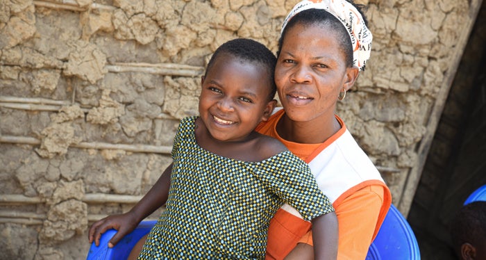 In the Democratic Republic of the Congo, a young girl smiles as she sits with a World Vision staff member. 